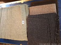 Three folded pieces of vintage Harris Tweed wool fabric shown together with tags numbered '44'.