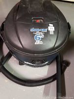 Top view of Shop Vac showing 6.5 gallon and 3.0 peak HP labels, with attached hose and plastic nozzle attachment.