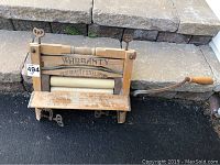 Front view of vintage wooden clothes wringer showing warranty and quality steel spring text.