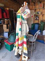Full-length photo of the Hudson Bay blanket coat on a wooden hanger stand with the stuffed bear attached.