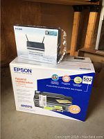 Photo showing boxed Epson CX8400 multifunction printer and boxed D-Link Wireless N300 router.