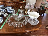 Photo of punch bowl with cups, ladles, crystal bowl and platter, and Spode ceramic pieces on wooden table