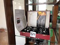 Red hinged case open on shelf, showing six crystal glasses, Moser brochure