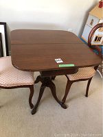 Full view of the rectangular wooden table with pivoting top and carved pedestal base.