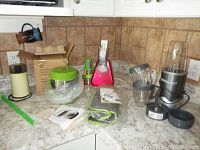 Countertop with garnishing tools, rice cooker, utensil, and NutriBullet blender with accessories