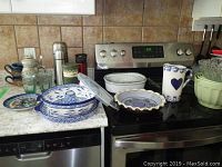 Wide view of dishes, thermoses, and other items on stove and counter
