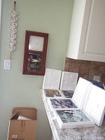 Wall clock mounted on wall showing wood frame and white clock face, with four porcelain tile boxes on countertop nearby