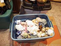 Plastic bin containing multiple teddy bears of various styles and sizes, some with tags, showing the full collection included in the lot.