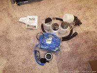 All accessories included in the spray system laid out on carpet, showing hoses, connectors, and manual.