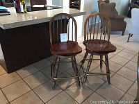 Two oak bar stools placed side by side in a kitchen setting, showing front and side views.
