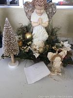 Photo showing Christmas angel centerpiece, bottle brush tree, angel door hanger, and greenery with gold accents