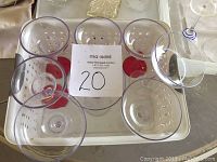 Set of eight clear acrylic margarita glasses arranged on a white tray, viewed from top.