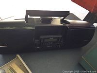 Front and top view of black Sirius radio player boombox with handle and speaker grills on both sides.