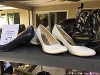 Various women's shoes including heels, sandals, and cowboy boots displayed on shelves with different styles and colors visible.