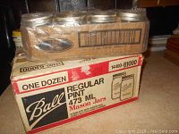 Box of 12 Ball Regular Pint 473 ml mason jars with lids and bands. The box shows some wear and is brown with red and beige labeling.