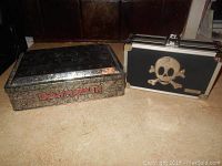 Photo showing both the Iron Maiden metal tin and the skull case side by side on a surface.