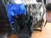 Three hiking backpacks in various colors; two have metal frames visible, one black-green Highpoint backpack in front.