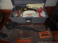 Closed gray plastic Mastercraft toolbox with tool belt in front on wooden floor
