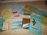 Photo showing assortment of vintage airline brochures, tickets, folded map, and playing cards deck.