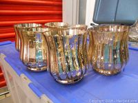 Close-up view of five gold mercury glass candle holders showing their ribbed, fluted design and reflective metallic finish.