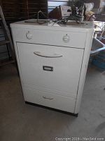 Front full view of white vintage Sunshine compact stove with oven and two burners on top, control knobs on front, enamel shows wear and age.