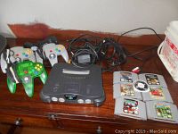 Overall lot on wooden surface: console, controllers, cables, games