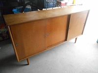 Three quarter angled view of the wooden sideboard showing three sliding doors with finger pull holes and short tapered legs.