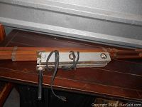 Wooden tripod camera holder with extendable legs and metal fittings, folded open on a wooden surface.
