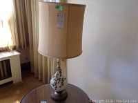 Full view of table lamp showing height, lampshade, and base on a reflective round table.