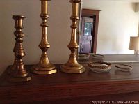 Front view showing both brass candlesticks and both glass ashtrays arranged on wooden surface.