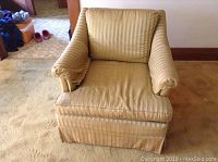 Full front view of beige fabric armchair with striped cushions and padded armrests on carpeted floor.
