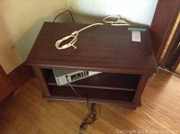 Wooden TV stand showing top and shelving space with cords visible.