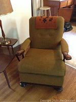 Front view of the green fabric rocking chair with wooden arms and brown leather headrest cover