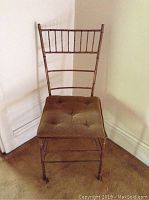 Front view of metal chair with decorative backrest and tufted cushion seat.