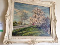 Oil on board landscape painting depicting rural scene with blooming tree and road, framed in ornate cream-colored frame