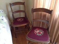 Pair of wooden chairs with curved backs and needlepoint floral seat upholstery in a warm room corner