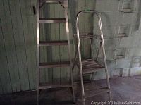 Photo showing the side view of two aluminum ladders, a taller extension ladder at 72 inches and a smaller step ladder at 54 inches side by side.