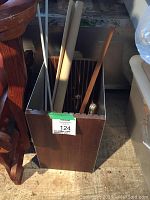 Wooden slide cabinet containing metal rods, curtain rods, and window blind rolled up
