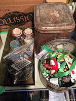 Overview photo showing large rectangular antique tin, assorted glass jars, and a round antique tin with sewing ribbons inside
