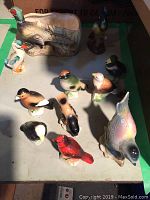 Display of small ceramic bird figurines arranged on surface with a ceramic bird-shaped planter pot also visible.