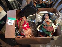Box containing various items including tablet, mat, doll, glass lamp shade, and other miscellaneous goods