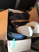 Box containing assorted items including ceramic bowl, basket, and sleeve ironing board