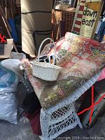 View of green and patterned carpet pieces, wicker basket on top, surrounding various bags and furniture