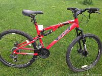 Side view of red CCM full suspension mountain bike on grass