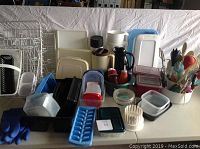 Overview of assorted kitchen items including milk jugs, storage containers, dish racks, and utensils on table