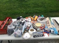 Wide shot of table with assorted tools, electrical supplies, safety items, and flashlights clearly visible