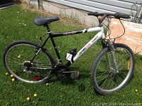 Full side view of Sportek Tempest mountain bike on grass showing frame, tires, seat, and handlebars.