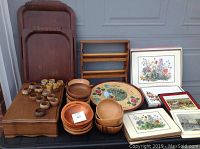 Wide shot showing wooden trays, wooden bowls, framed prints, small napkin rings, silverware chest, and wooden towel dispenser.