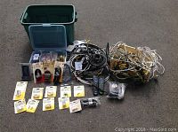 Wide view showing loose cables, many new coaxial connectors in packaging, Bell brand remotes, and a plastic tote.