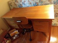 Desk and chair positioned against wall with mattress in background
